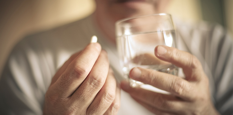 Man about to take medication with glass of water